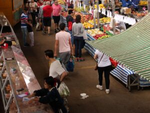 Pessoas na feira, circulando entre as bancas, procurando por produtos